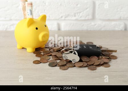 Chiave dell'auto, salvadanaio e monete su sfondo chiaro Foto Stock