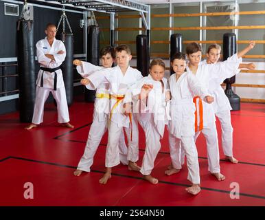 Gruppo di bambini con man trainer in posa in palestra dopo taekwondo allenamento Foto Stock
