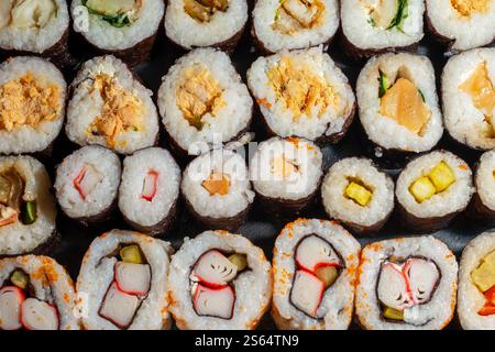 Variopinto assortimento di sushi roll disposti in file Foto Stock