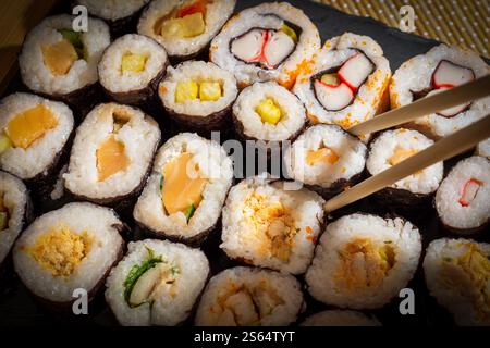 Sushi roll assortiti serviti nel vassoio di ardesia Foto Stock