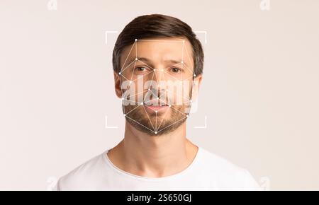 Un uomo si trova su uno sfondo chiaro, mostrando la tecnologia di riconoscimento facciale Foto Stock