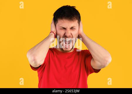 Giovane arrabbiato urlando e afferrando la testa Foto Stock