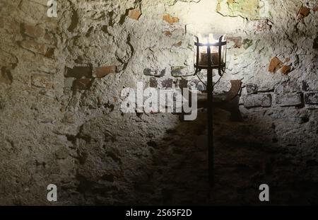 Torcia del castello medievale illuminata appesa su un muro di pietra, oggetti d'epoca e sfondo. Torcia medievale illuminata appesa su un muro di pietra, vintage Foto Stock