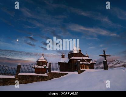 Notte cielo mith Luna sopra campagna remota chiesa villaggio sulla cima collina. Ucraina, Voronenko. Foto Stock