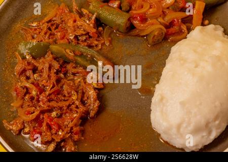 Matemba o Kapenta Fish (Limnothrissa miodon, Lake Tanganyika Sardine) e okra Stew servito con pasta di mais Foto Stock