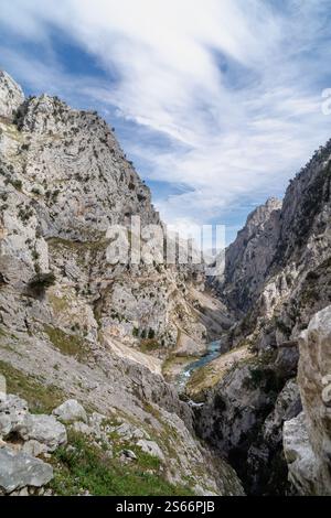 Una catena montuosa con un fiume che la attraversa. Il cielo è limpido e blu. Le montagne sono coperte di neve e il fiume scorre attraverso un vall Foto Stock