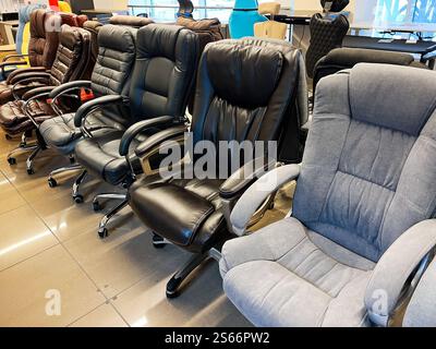 Una selezione di sedie ergonomiche da ufficio disposte in uno showroom, con stili, materiali e colori diversi per ambienti professionali o domestici Foto Stock