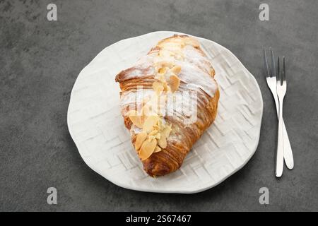Croissant alle mandorle con zucchero a velo sul piatto bianco Foto Stock
