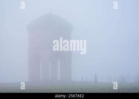 Una persona cammina accanto al mulino a vento di Chesterton durante la nebbia a Chesterton nel Warwickshire. È entrato in vigore un allarme giallo per la nebbia, con l'avviso dell'Ufficio MET che il tempo potrebbe causare interruzioni del viaggio, inclusi ritardi o cancellazioni dei voli. Data foto: Giovedì 16 gennaio 2025. Foto Stock