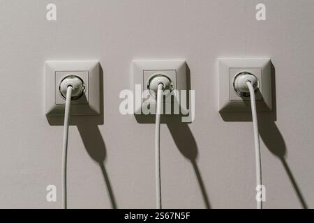 prese elettriche bianche con spine. collegamento del filo ad alta tensione alla presa Foto Stock