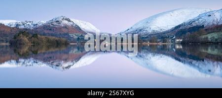 Le colline innevate che circondano il pittoresco villaggio di Grasmere si riflettono in un panorama dell'alba in una mattinata gelida nel Lake District. Foto Stock