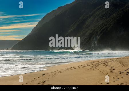 Onde che si infrangono sulla spiaggia sabbiosa di Quintay Beach in Cile durante una giornata luminosa e limpida Foto Stock