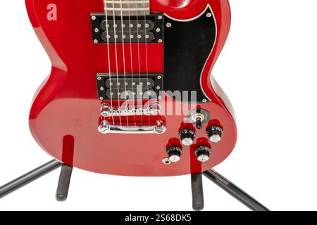 Una chitarra elettrica rossa con un ponte nero e un picchetto nero. La chitarra è su uno stand ed è al centro dell'attenzione Foto Stock