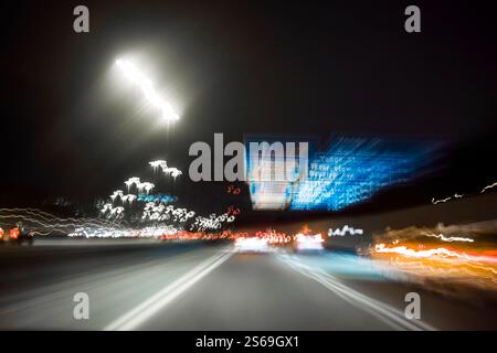 Auto, segnali e luci sull'autostrada notturna della città, sfocatura del movimento creata dalla fotografia a lunga esposizione Foto Stock