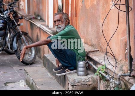 Uomo indiano in strada sui suoi fianchi con un tiffin (pasto leggero) container a Jaipur, India. Foto Stock