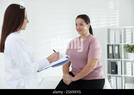 Nutrizionista con appunti che dà raccomandazioni alla donna in sovrappeso in ospedale Foto Stock