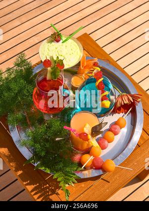 Cocktail estivi colorati e rinfrescanti con guarnizione di frutta su un tavolo all'aperto Foto Stock