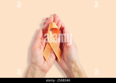 Nastro arancione per la consapevolezza del cancro nelle donne mani su sfondo bianco Foto Stock