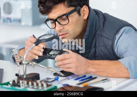 ingegnere informatico che lavora su una console rotta nel suo ufficio Foto Stock
