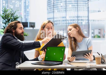 Clienti che cercano una guida personalizzata alla pianificazione su un notebook con schermo verde scritta dal consulente finanziario durante la riunione. Consulente che ottimizza le spese di vita per i clienti utilizzando un notebook mockup Foto Stock