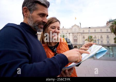 Allegra coppia matura che cerca insieme una mappa cartacea alla ricerca di un luogo durante il viaggio. Foto Stock