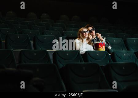 Una coppia si diverte a una serata al cinema con popcorn in un cinema quasi vuoto Foto Stock