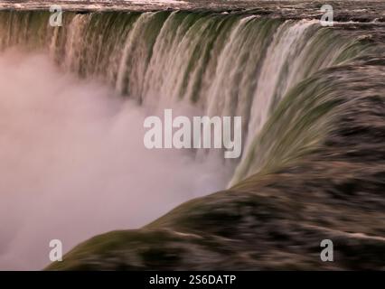 Una vista dettagliata delle Cascate del Niagara cattura l'acqua a cascata che si tuffa in un abisso pieno di nebbia, evocando potenza e serenità in egual misura. Foto Stock