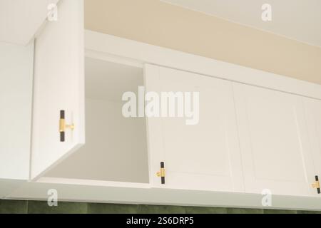 Eleganti armadietti da cucina bianchi con sportelli aperti per un facile accesso e stile Foto Stock
