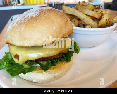 Hamburger vegano con formaggio e un contorno di patatine fritte. Foto Stock