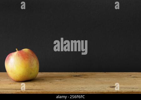 Un'immagine di un tavolo di legno di mela su sfondo nero Foto Stock