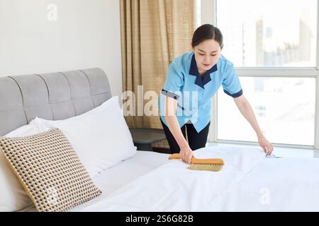 Donna che pulisce il letto Foto Stock