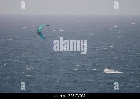 Un kiteboarder che viene tirato sull'acqua da un aquilone. Los Cristianos. Tenerife. Isole Canarie. Spagna. Foto Stock