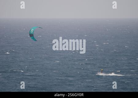 Un kiteboarder che viene tirato sull'acqua da un aquilone. Los Cristianos. Tenerife. Isole Canarie. Spagna. Foto Stock