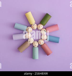 Immagine di emozioni diverse su bambole di legno su sfondo viola. Stile piatto. Vista dall'alto. Foto Stock