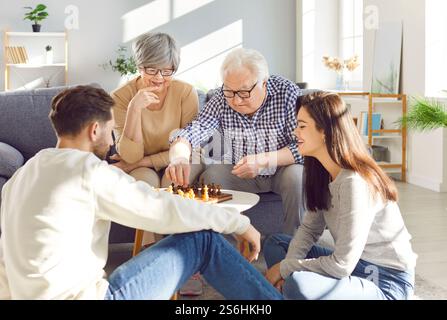 Famiglia felice che gioca a scacchi insieme nel soggiorno Foto Stock