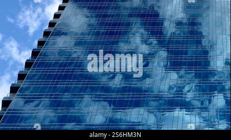 Nuvole che si riflettono nelle finestre di un moderno edificio per uffici Foto Stock
