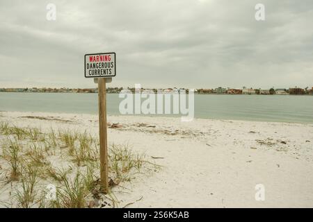 Avviso correnti pericolose segnalano il cartello di Pass A Grille Dog Beach. Guardando verso Bay Channel. Sulla sabbia e sull'avena verde del mare. St. Pete Beach, Florida, su un clo Foto Stock