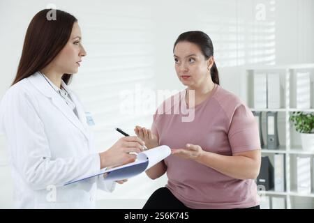 Nutrizionista con appunti che dà raccomandazioni alla donna in sovrappeso in ospedale Foto Stock