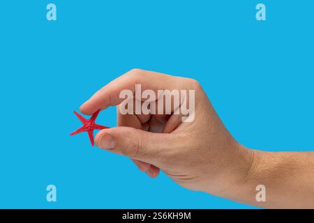 Mano che tiene le stelle marine rosse isolate su sfondo blu. Copia spazio Foto Stock