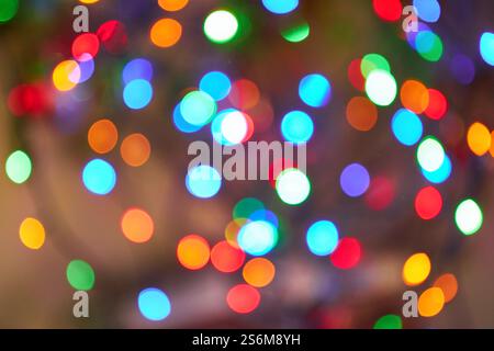 Le luci bokeh natalizie in vari colori creano uno sfondo vivace e gioioso. L'immagine presenta forme circolari sfocate in verde, rosso, blu, arancione, Foto Stock