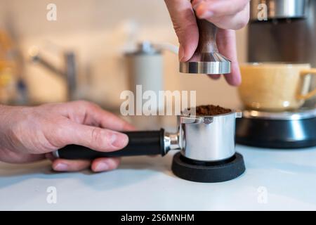 Barista Tamping caffè appena macinato per espresso Foto Stock