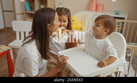 Madre e due figli condividono un momento di amore mentre il figlio offre una banana alla madre in un'accogliente camera da letto, mostrando caldi legami familiari e tog Foto Stock