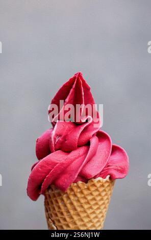 Un cono di gelato riempito con un delizioso gelato soffice al lampone appena preparato Foto Stock