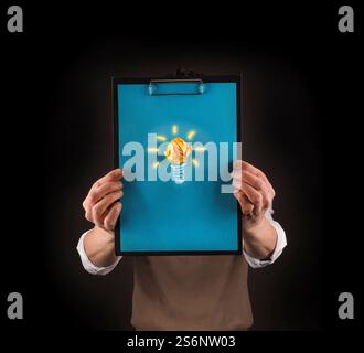 Business man tenendo un clipboard con disegnato a mano la lampadina di luce su di esso Foto Stock