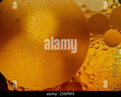 Le bolle d'olio sospese in un liquido dorato creano un modello affascinante e artistico. Foto Stock