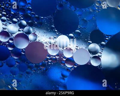 Immagine dinamica della miscela blu di olio e acqua, che mostra bolle e tensione superficiale in schemi astratti. Foto Stock