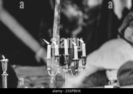 Un portacandele con cinque candele. Le candele sono accese e il supporto è argento. La scena è calda e accogliente Foto Stock