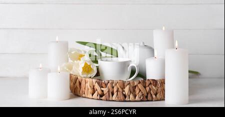 Candele accese, teiera, tazza e splendidi fiori di tulipani sul tavolo bianco Foto Stock