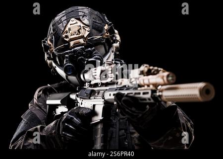 Un soldato militare altamente equipaggiato, che punta un fucile con ottiche high-tech, indossa un casco tattico e un equipaggiamento, mostrando prontezza e fuoco di combattimento a. Foto Stock