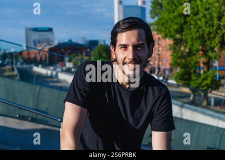 Giovane latino in piedi sorridente rilassato e calmo in città Foto Stock